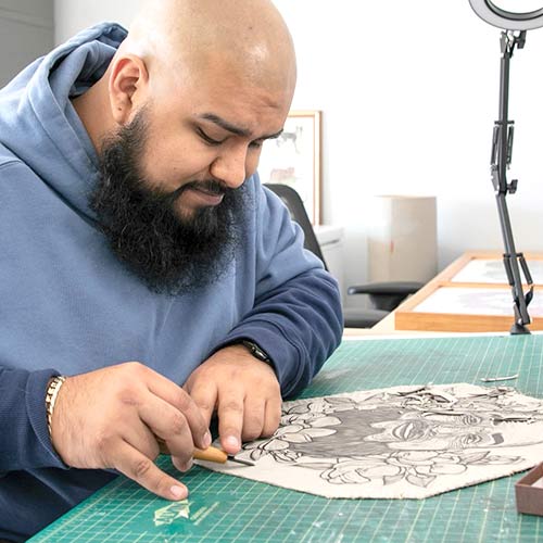 Portrait of artist, Frank Estrada, carving a printmaking block.
